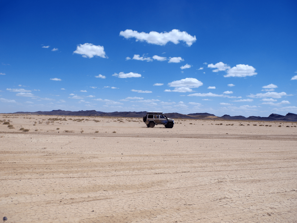 photo d'un 4x4 prise de loin sur le sable avec un beau ciel bleu