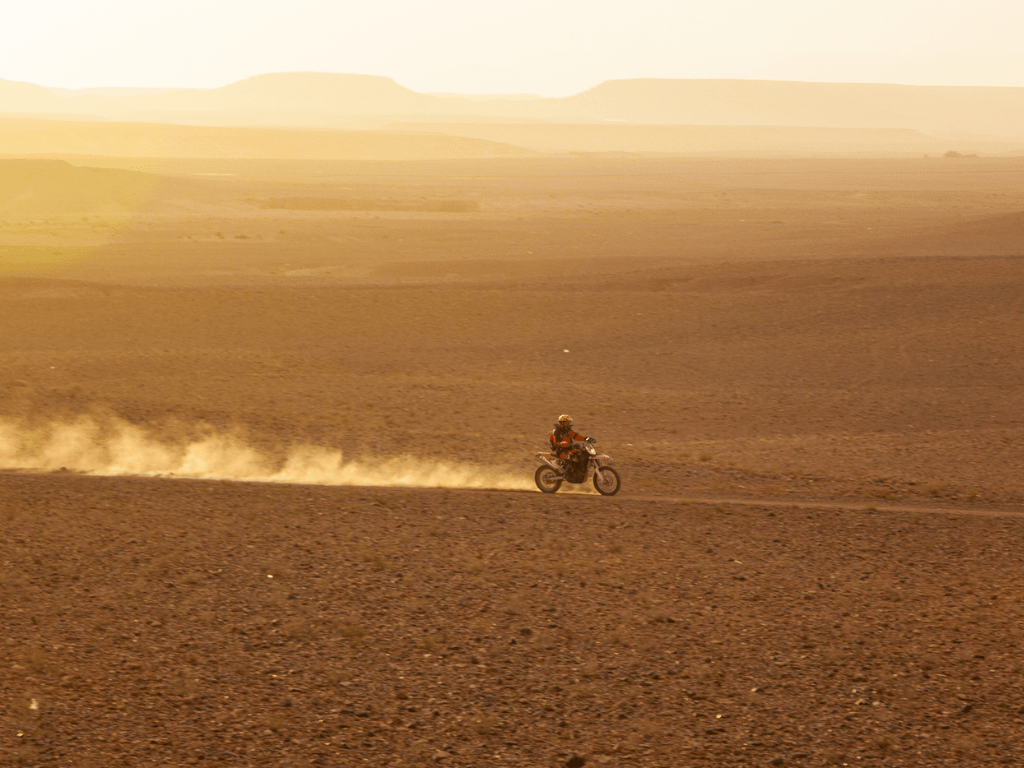 Moto laissant une trainée de sable en parcourant les dunes du Maroc
