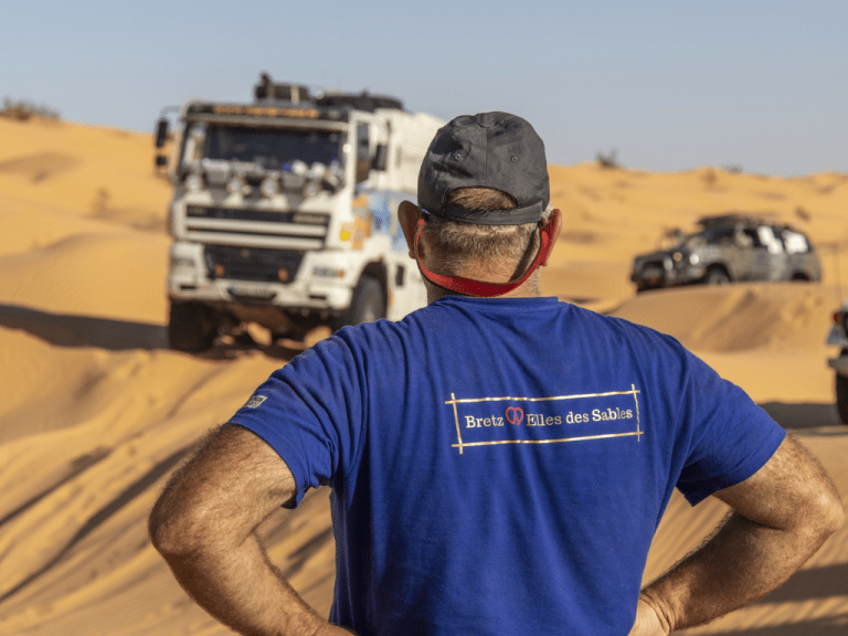 Photo de dos de Jacky Lechleiter avec le camion d'assistance en fond