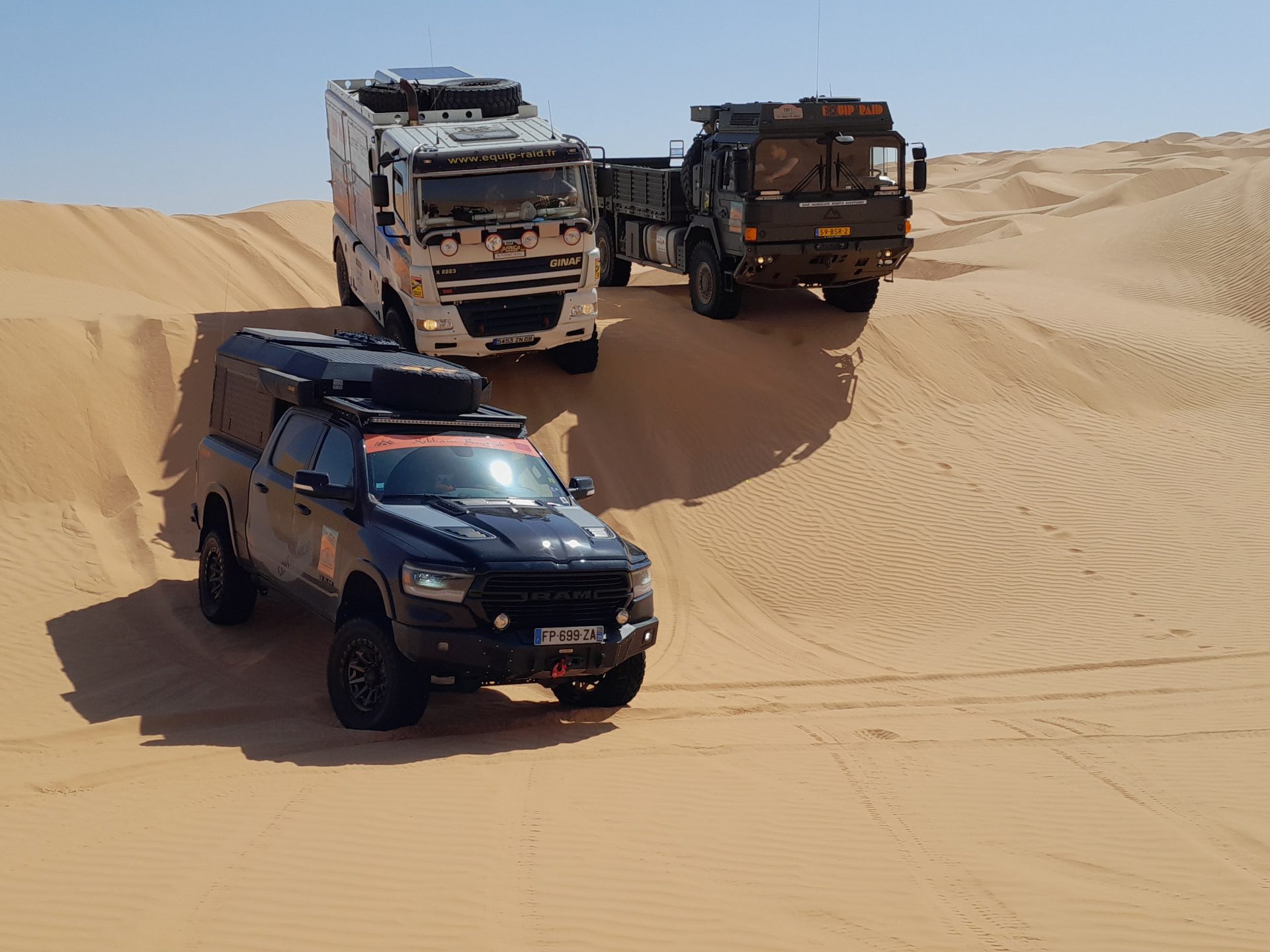 Photo des deux camions d'assistances et un 4x4 noir dans le désert