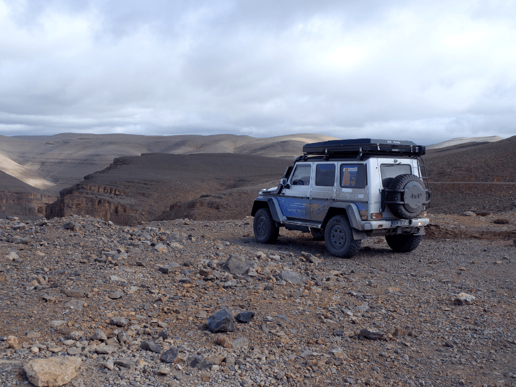 Photo d'un 4x4 prise de dos avec un beau paysage des dunes marocains