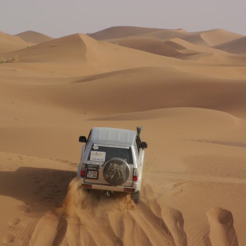 Photo de dos d'un 4x4 qui traverse les dunes lors d'un raid au Maroc