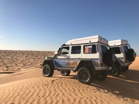 On voit 2 véhicules d'assistance de course dans les dunes